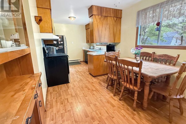 Kitchen and dining area with light wood cabinets, a black stove, and a wooden table with chairs. - 26 South Hill Drive, Abercrombie