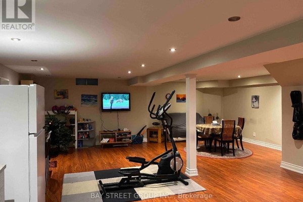 Finished basement recreation room with wood floors, exercise equipment, and dining table. - 26 Stave (lower) Crescent, Richmond Hill