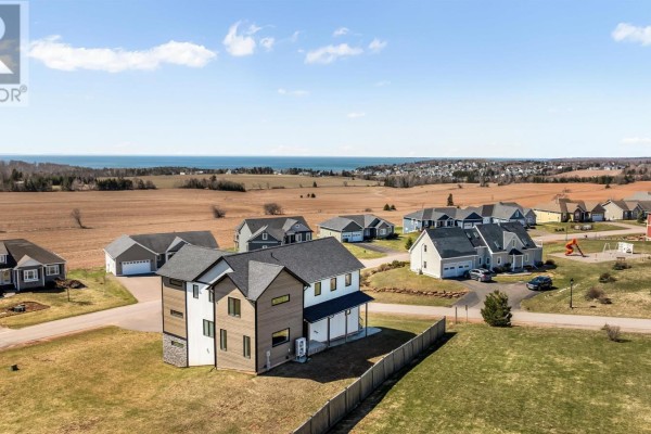 Aerial view of a modern house with a large yard, surrounded by a suburban neighborhood and ocean view. - 26 Strawberry Lane, Stratford