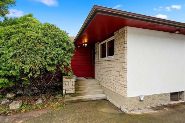 Concrete steps leading to a red front door with stone and white exterior walls. - 26 Waterford Bay, Winnipeg