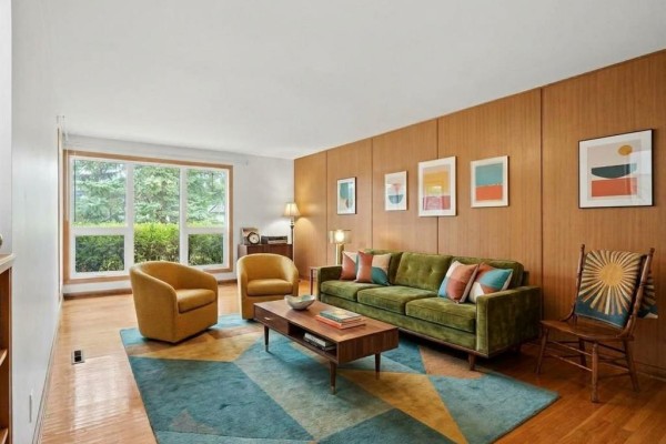 Living room with green sofa, yellow chairs, coffee table, and colorful abstract art. - 26 Waterford Bay, Winnipeg