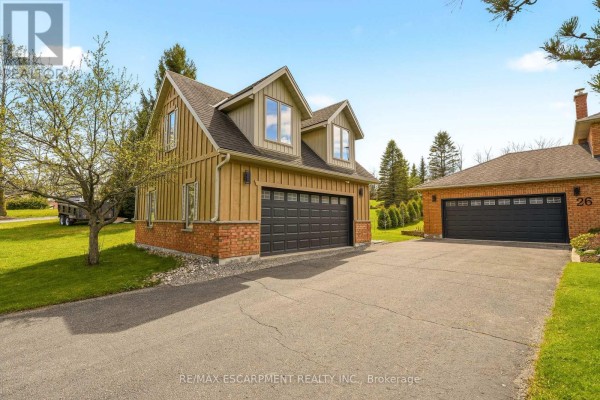 Two-car garage with wood siding and brick base, adjacent to a driveway and single-car garage. - 26 Weneil Drive, Hamilton