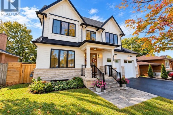 Front view of a two-story white farmhouse with black trim and landscaping. - 260 Kent Crescent, Burlington