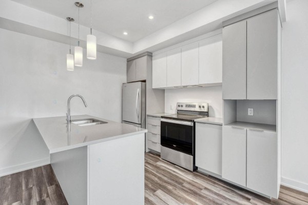 Contemporary kitchen with light grey cabinets, stainless steel appliances, island, and quartz countertops. - 260 Rue Nancy-elliott, #101, Gatineau