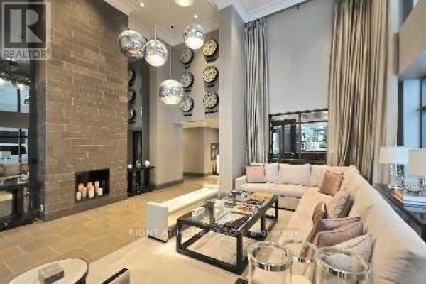 Lobby with a long sectional sofa, coffee table, fireplace, and multiple world clocks on the wall. - 2601 - 35 Hayden Street, Toronto