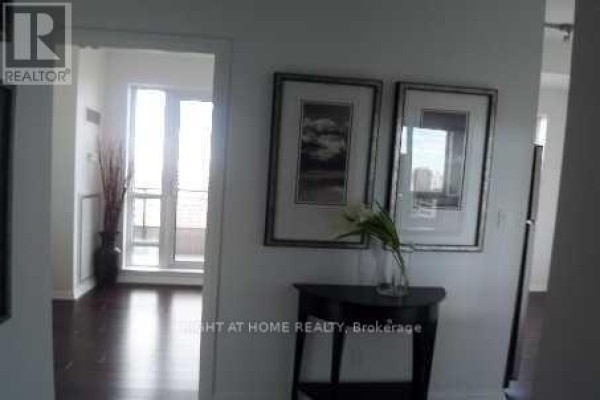 Hallway with dark hardwood floors, framed artwork, and a glimpse of a balcony through a doorway. - 2601 - 35 Hayden Street, Toronto