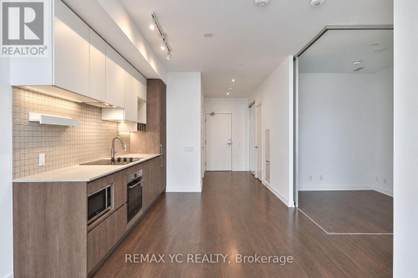 Open concept living space with a modern kitchen and view into a separate room through a glass partition. - 2601 - 898 Portage Parkway, Vaughan