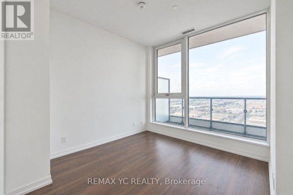 Bedroom with large windows providing an expansive city view and dark wood flooring throughout. - 2601 - 898 Portage Parkway, Vaughan