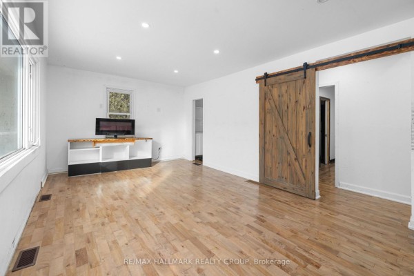 Living area with hardwood floors, natural light from windows, and a barn door. - 2601 Regional Road 174 Road, Ottawa