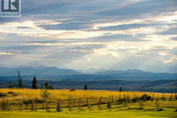Expansive view of rolling hills and distant mountains under a cloudy sky. - 260169 Mountain Ridge Place, Rural Rocky View County