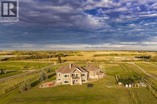 Rear exterior of the house showing a large backyard and surrounding fields. - 260169 Mountain Ridge Place, Rural Rocky View County