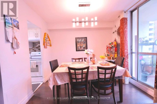 Dining room with table set for four, chairs, pendant light, and view into kitchen. - 2603 - 1 Massey Square, Toronto
