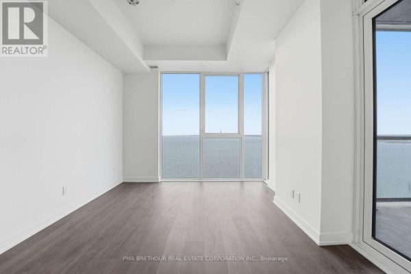 Bright living room with floor-to-ceiling windows offering a panoramic view of the lake and city. - 2603 - 370 Martha Street, Burlington