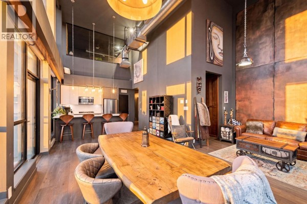 Dining room with a large wooden table, bench, and upholstered chairs, overlooking the city. - 2603 271 Francis Way, New Westminster