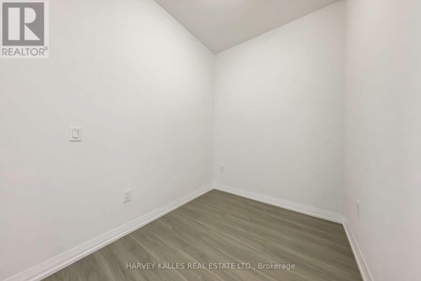 Empty room with white walls, grey wood-look flooring, and a light switch. - 2604 - 25 Holly Street, Toronto