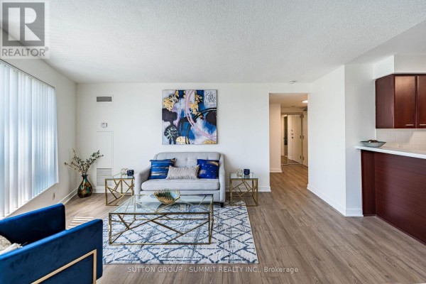 Living room with a sofa, coffee table, and view into a hallway and kitchen area. - 2605 - 38 Lee Centre Drive, Toronto