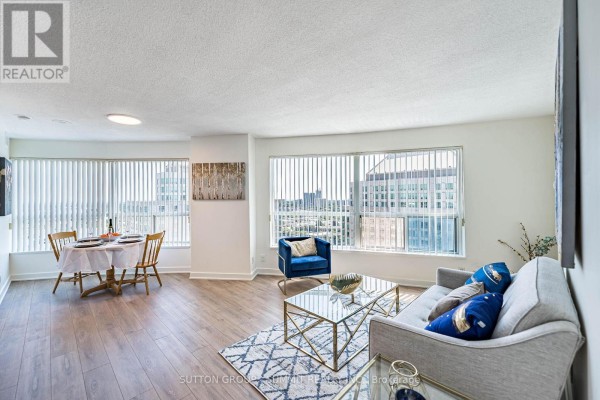 Apartment living and dining area with large windows, blinds, and city views. - 2605 - 38 Lee Centre Drive, Toronto