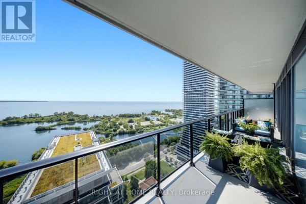 View from apartment balcony showing a lake, green spaces, and tall buildings. - 2605 - 70 Annie Craig Drive, Toronto