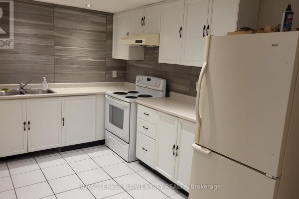 Kitchen with white cabinets, white appliances, and grey wood-style backsplash. - 2605 Innisfil Road, Mississauga