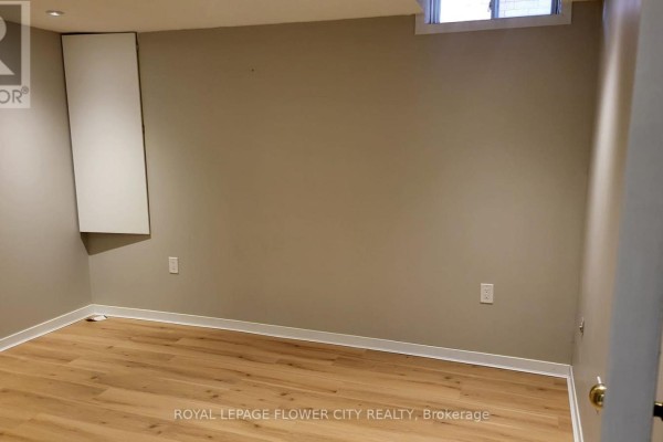 Empty room with beige walls and light wood laminate flooring. - 2605 Innisfil Road, Mississauga