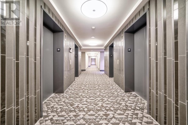 Hallway with grey elevators, patterned carpet, and vertical textured wall panels. - 2607 - 10 York Street, Toronto