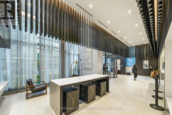 Modern lobby with marble desk, black stools, chairs, and a glass partition. - 2608 - 4065 Confederation Parkway, Mississauga