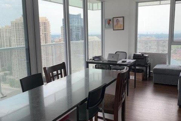 Dining area with a large table, chairs, and city view through floor-to-ceiling windows. - 2608 - 4065 Confederation Parkway, Mississauga