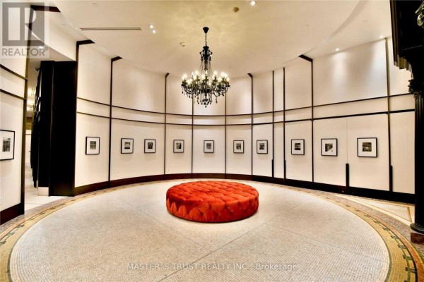 Circular lobby with mosaic tile floor, artwork on curved walls, and orange ottoman. - 2609 - 197 Yonge Street, Toronto