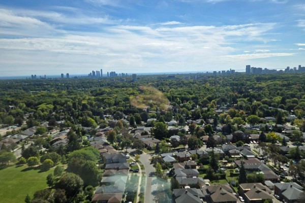 Aerial view of suburban neighborhood with houses and trees, extending to a distant city skyline. - 2609 - 4010 Eglinton Avenue W, Toronto
