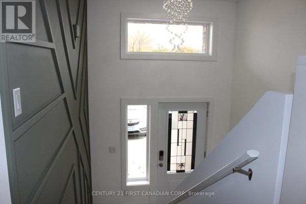 Interior entryway with modern chandelier, large window, and decorative wall paneling. - 2609 Oil Heritage Road, Oil Springs