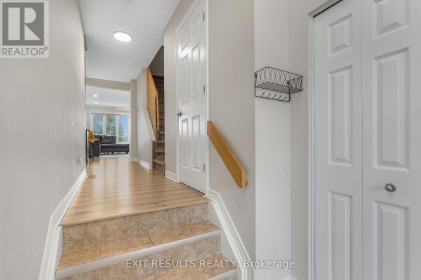 Interior hallway looking towards the living area, featuring a staircase with tiled steps and wood banister. - 2609 Raymond Street, Clarence Rockland