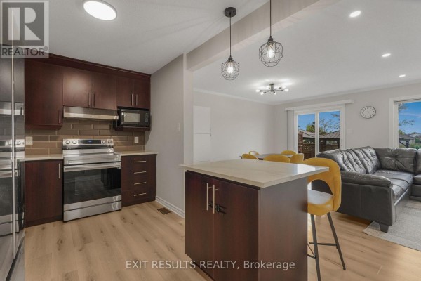 Modern kitchen with dark wood cabinets, stainless steel appliances, and an island with seating. - 2609 Raymond Street, Clarence Rockland