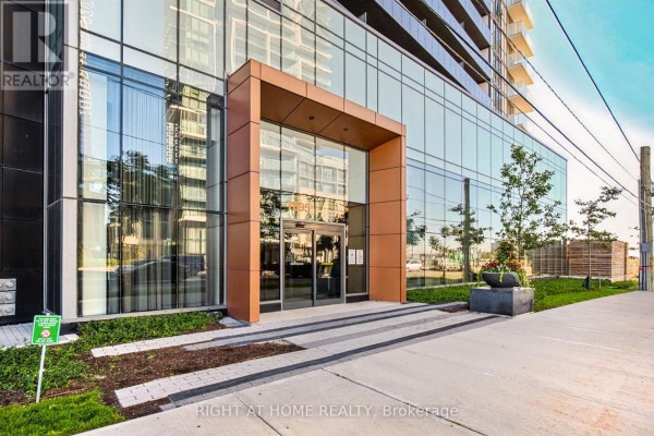 Glass-fronted building entrance with modern wood and copper accents. - 2617 - 7895 Jane Street, Vaughan