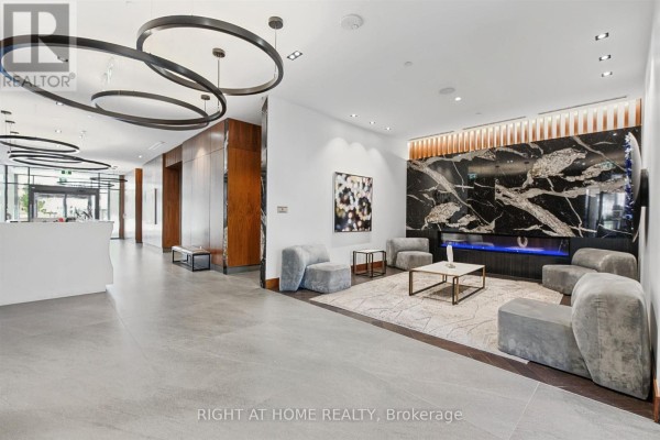 Building lobby with contemporary furniture, marble fireplace, and pendant lighting. - 2617 - 7895 Jane Street, Vaughan