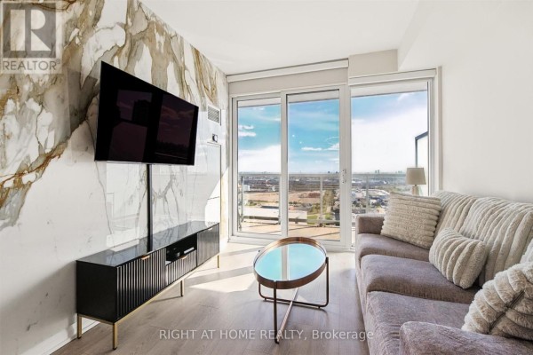 Apartment living room with marble accent wall, sofa, and city view. - 2617 - 7895 Jane Street, Vaughan