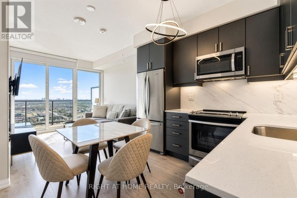 Apartment kitchen with dark cabinets and stainless steel appliances, adjacent to dining area. - 2617 - 7895 Jane Street, Vaughan