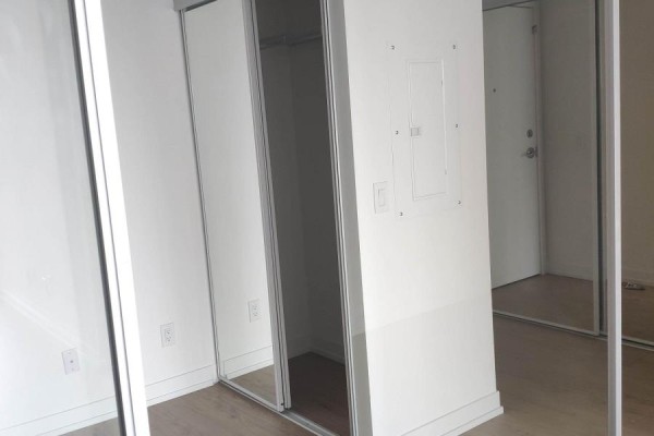 Hallway with mirrored closet doors and a white door visible. - 2617 - 85 Wood Street, Toronto