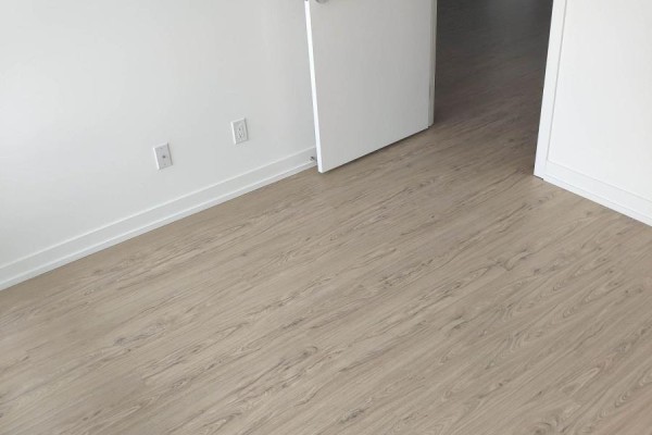 Interior corner with white walls and light wood-look laminate flooring. - 2617 - 85 Wood Street, Toronto