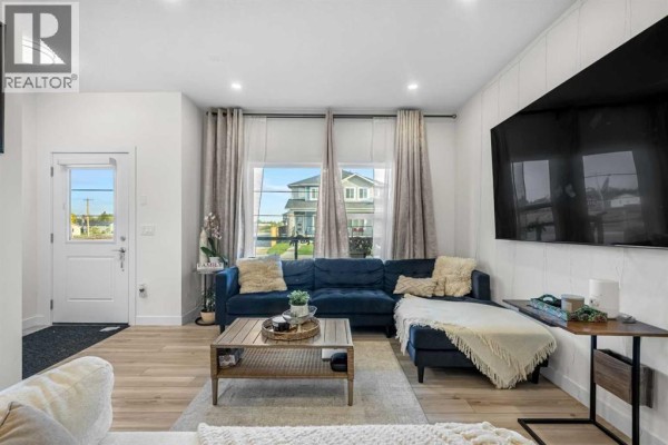 Living room with wicker furniture, a patterned rug, and a geometric chandelier. - 262 Midgrove Mews Sw, Airdrie