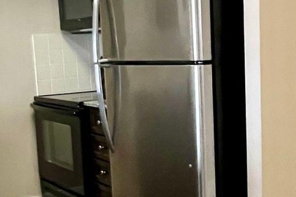 A stainless steel refrigerator and black stove are visible in the galley kitchen. - 2621 - 135 Village Green Square, Toronto