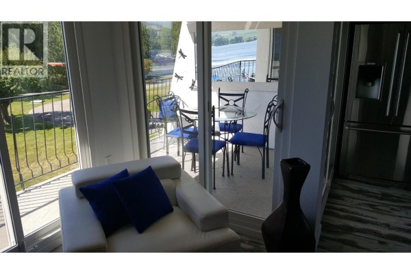 Living area with white sofa and view of balcony with lake. - 2621 85th Street Unit# 202, Osoyoos