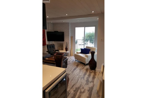 Living room with fireplace, TV, white sofa, and lake view. - 2621 85th Street Unit# 202, Osoyoos