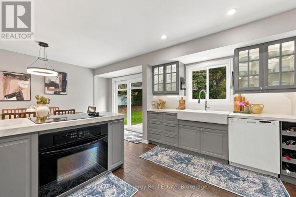 Modern gray kitchen with white countertops, stainless steel appliances, and a large window above the sink. - 2621 Division Street N, Cobourg