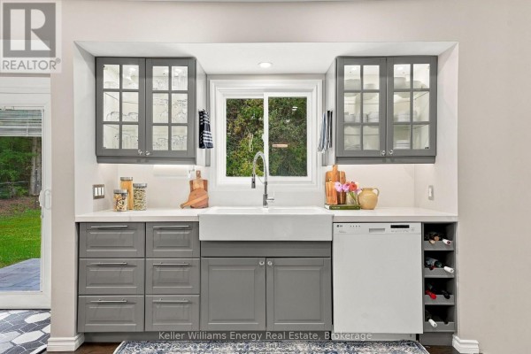 Detail of the farmhouse sink area in the gray kitchen, featuring glass-front cabinets and wine storage. - 2621 Division Street N, Cobourg