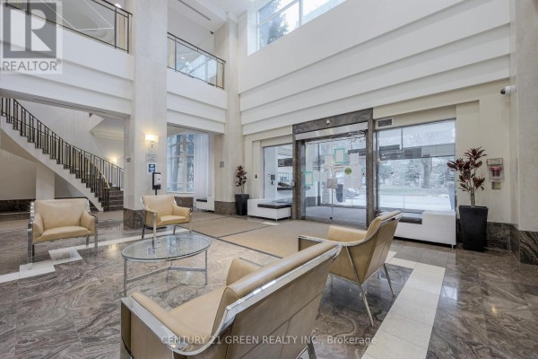 A modern building lobby with seating, a glass coffee table, and elevator doors. - 2623 - 68 Corporate Drive, Toronto