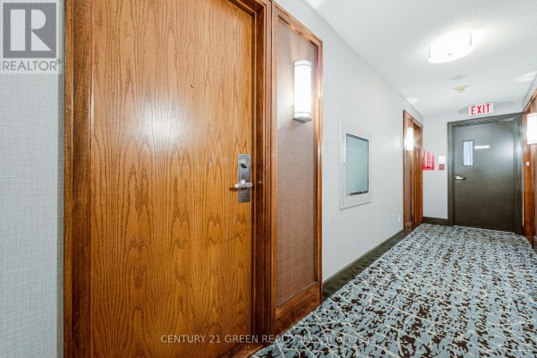 Apartment hallway with wood doors, patterned carpet, and wall-mounted lighting fixtures. - 2623 - 68 Corporate Drive, Toronto