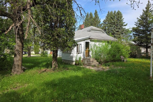 Side view of the white house, showing siding, windows, and garage attached to the left. - 263 Griffin Street, Treherne
