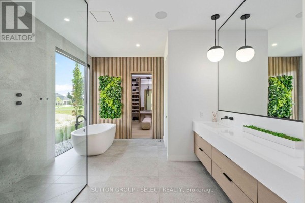 Spacious bathroom with freestanding tub, large window, double vanity, and walk-in closet entrance. - 263 Silver Maple Circle, Thames Centre