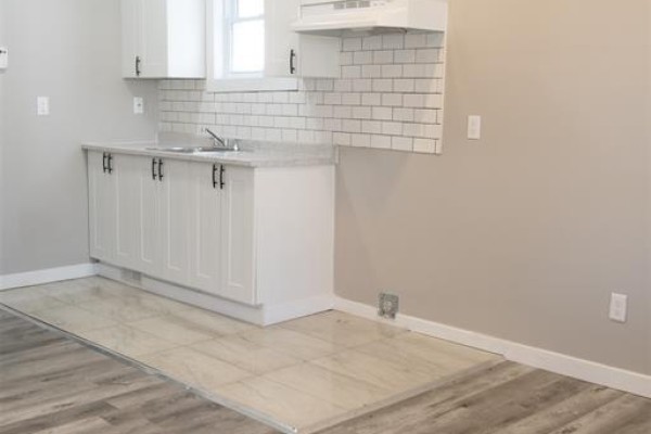 A small kitchen with white cabinets, subway tile backsplash, and light grey walls. - 263 Tuscarora Unit# Main, Windsor
