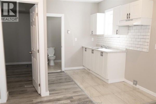 View of a kitchen and an open doorway leading to a small bathroom with a toilet. - 263 Tuscarora Unit# Main, Windsor